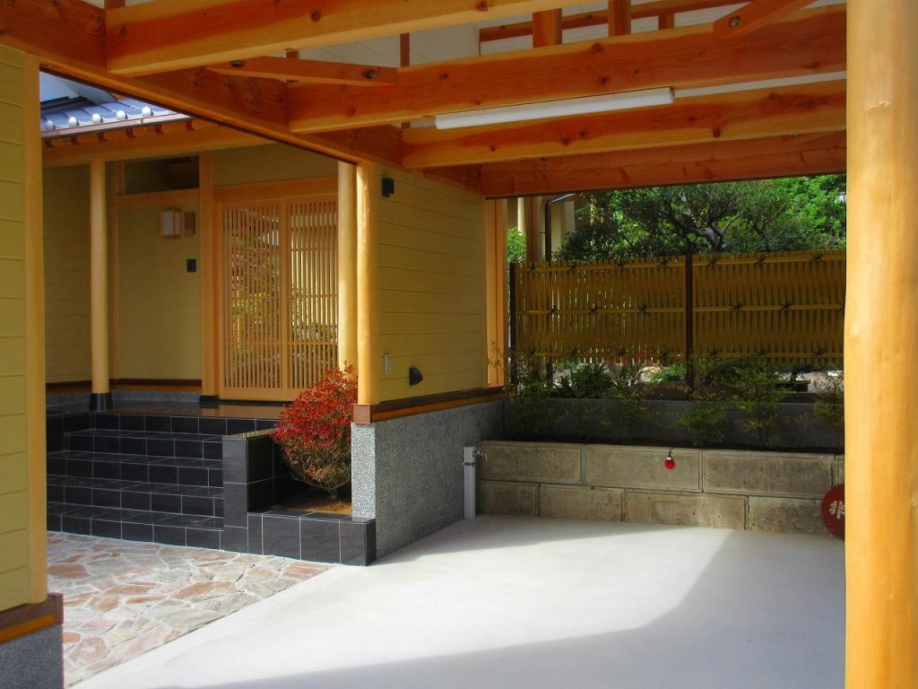 本宅へと続く石畳のアプローチ。格式ある門、そして車庫。【やねきハウスの新築注文住宅】：外観
